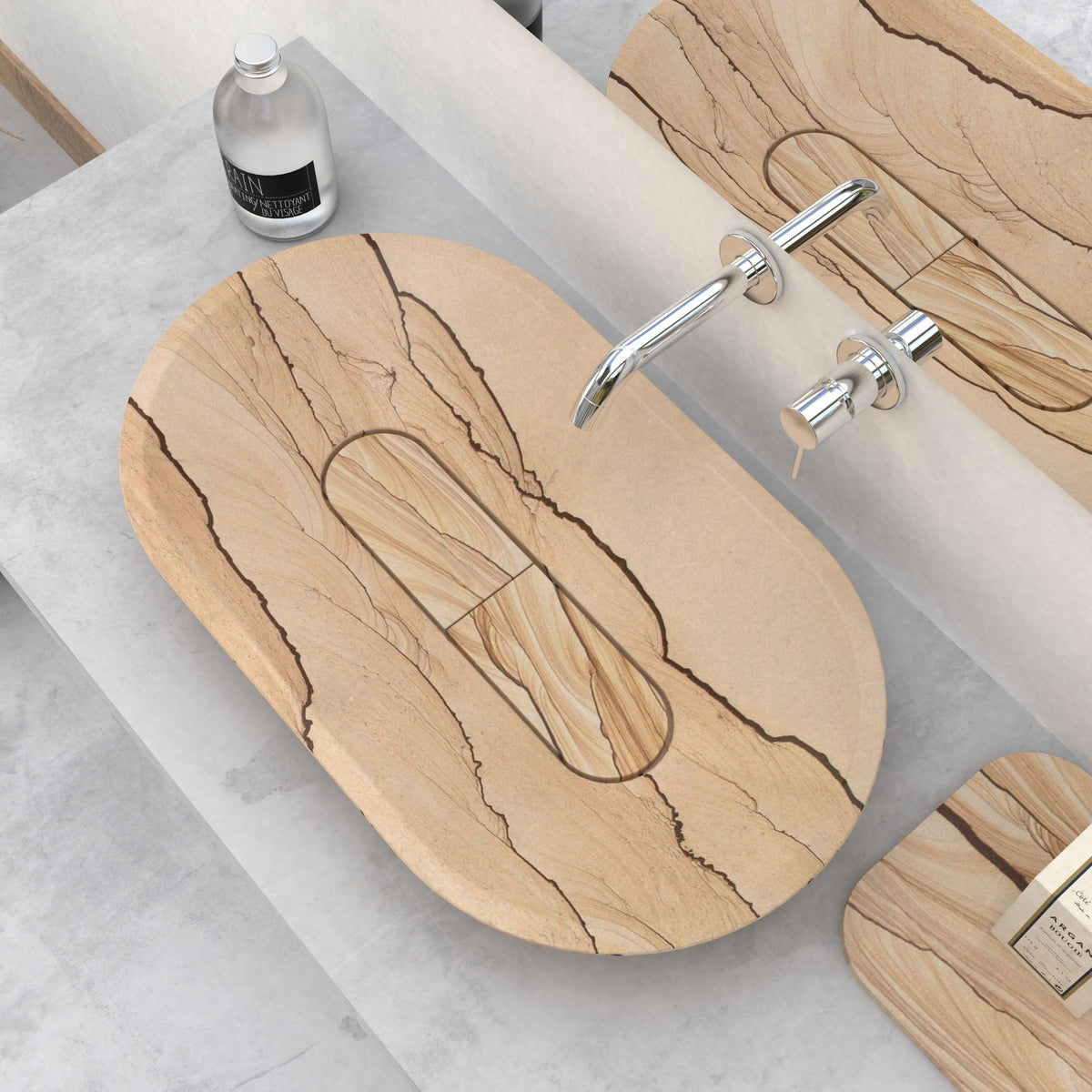 Selia oval sandstone vessel sink beneath a wall-mounted faucet, with the rim and basin interior visible in a styled bathroom scene.