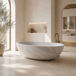 Yaris Carrara White Marble freestanding soaking bathtub in a bright architectural luxury bathroom