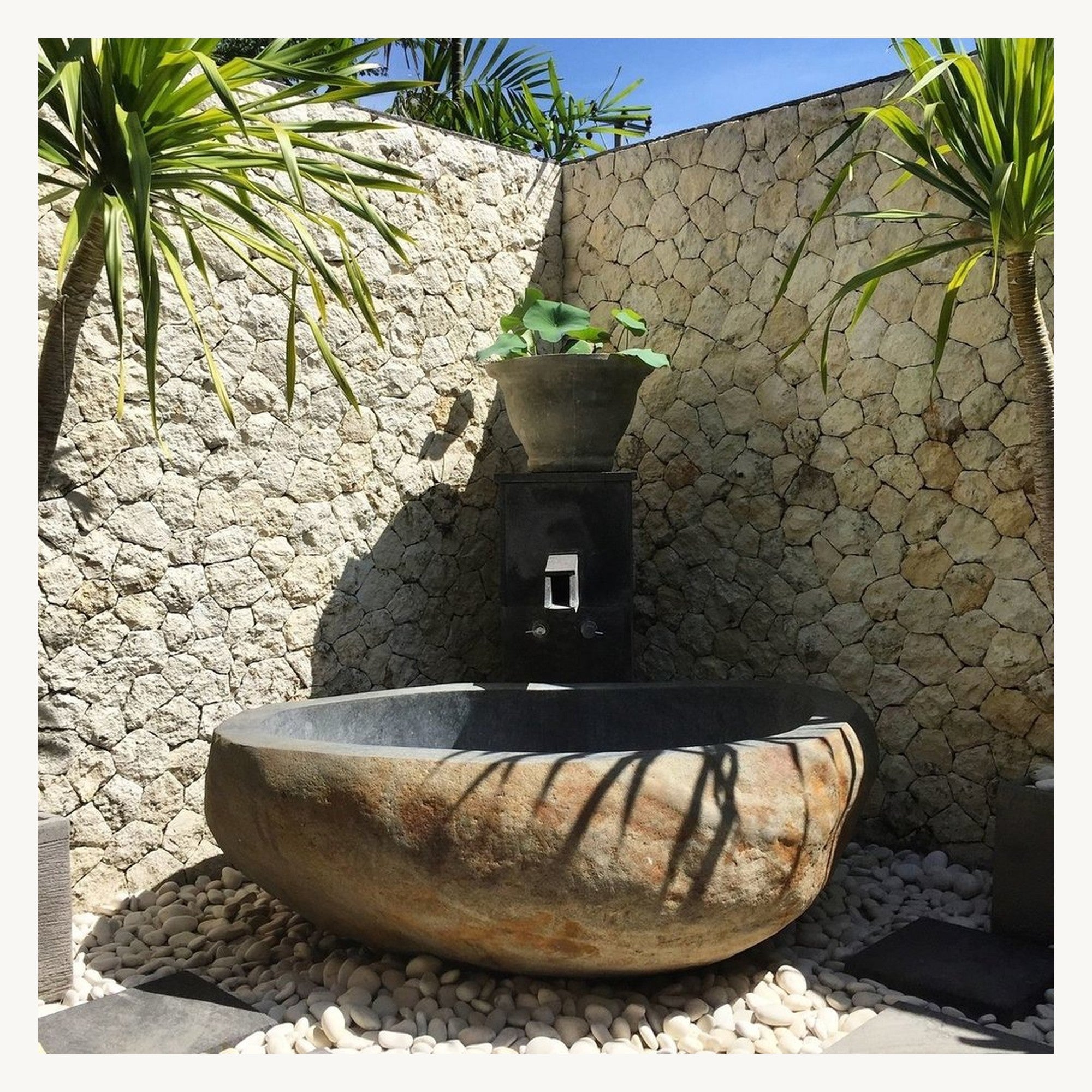 Actual Yitta Filetto Cobble Stone Granite bathtub in an outdoor stone bathroom setting