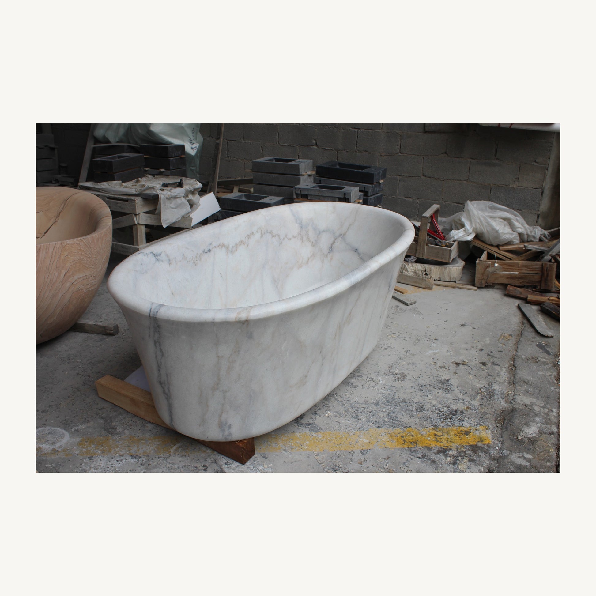 Actual Elara solid marble bathtub photographed at the stone workshop, angled view