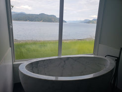 Actual installed Aurelia BT-038A marble bathtub beside a large window with lake view