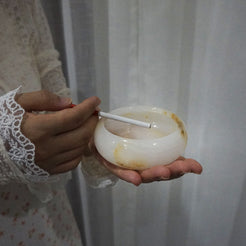 Person holding the Aura Onyx Ashtray with a cigarette, demonstrating its functionality as a stylish smoking accessory.