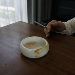 Aura Onyx Ashtray placed on a wooden table with a cigarette, blending seamlessly into a cozy and elegant setting.