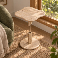 AeroCloud Classico travertine and acrylic side table in a window-side reading alcove, viewed from a higher oblique angle.