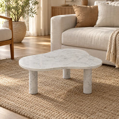 CloudDream Italian Carrara marble coffee table with a thin cloud-shaped top and three cylindrical legs in a warm linen-sofa living room.