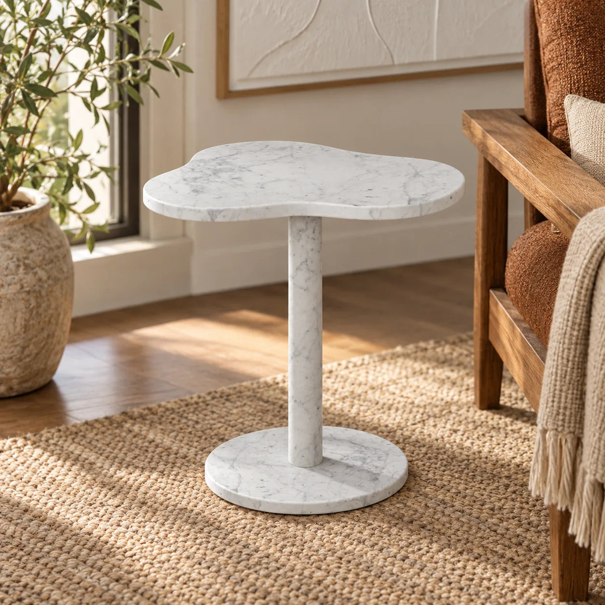 CloudDream Carrara marble side table with a cloud-shaped top and cylindrical pedestal beside a wooden reading bench.