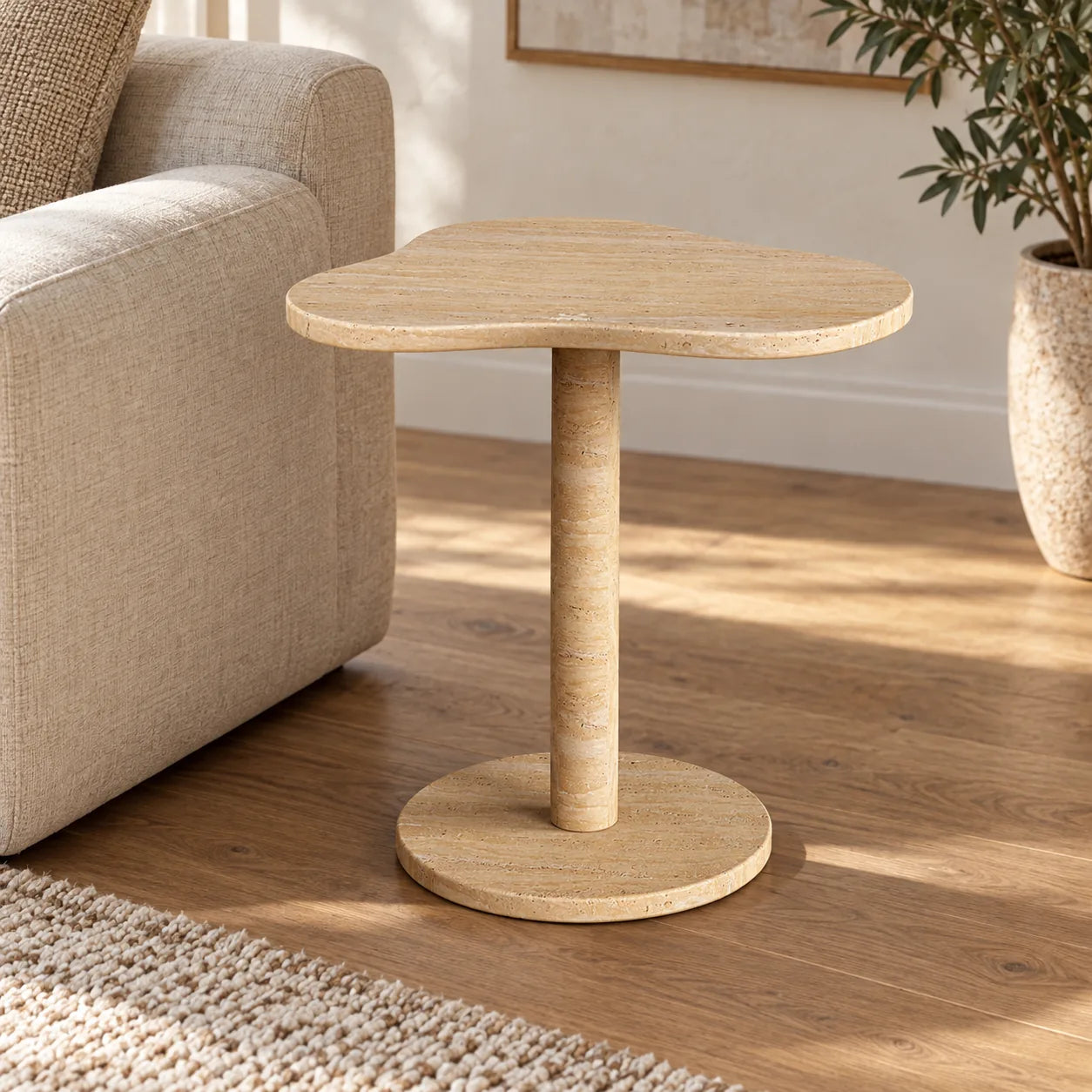 CloudDream Classico travertine side table with a cloud-shaped top and circular base beside a linen sofa.