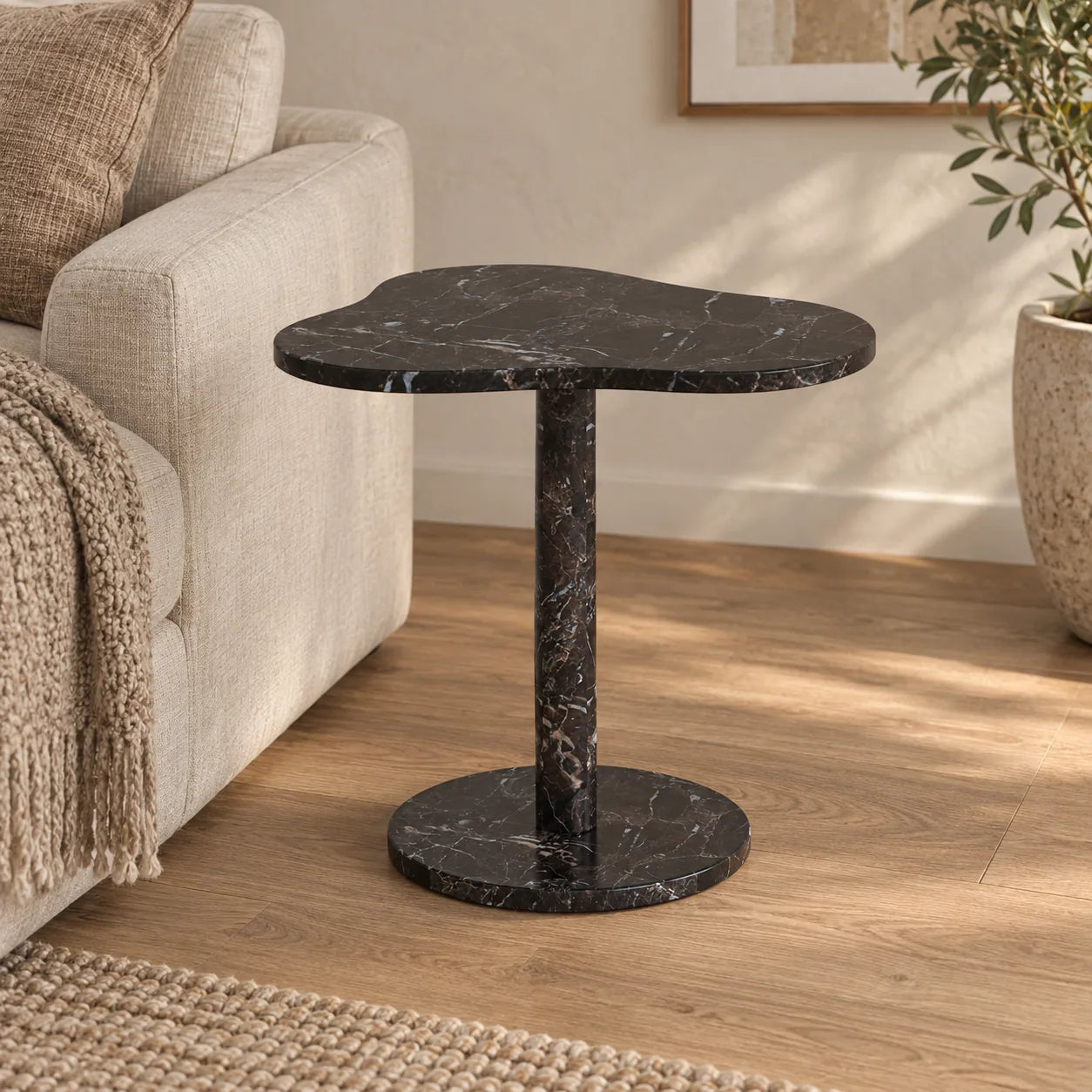 CloudDream Dark Emperador marble side table with a cloud-shaped top and circular base beside a linen sofa.