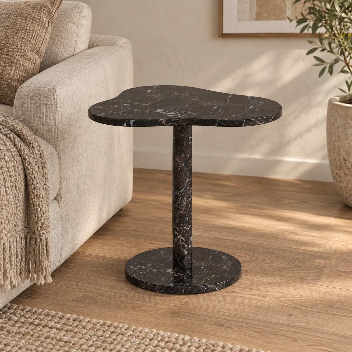 CloudDream Dark Emperador marble side table with a cloud-shaped top and circular base beside a linen sofa.