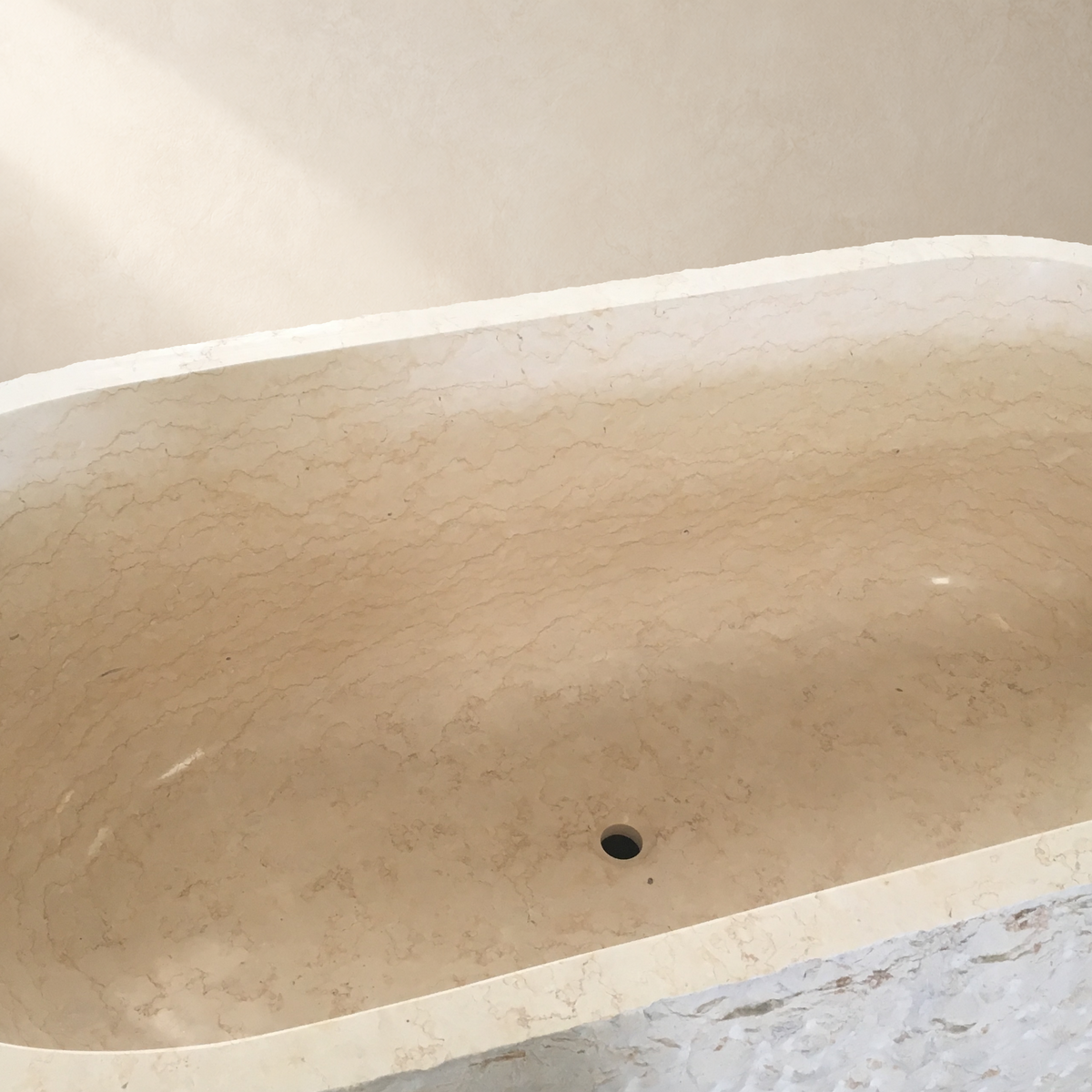 Dorienne BT-201A Golden Beige Marble bathtub, interior, circular drain and front rough-pick wall detail from product photograph IMG_8668 with a replaced neutral background; original marble texture and visible basin structure retained.
