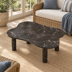 Elevated view of the LakeMist Dark Emperador marble coffee table in a garden-facing sunroom, showing its contoured rectangular top and four stone legs.