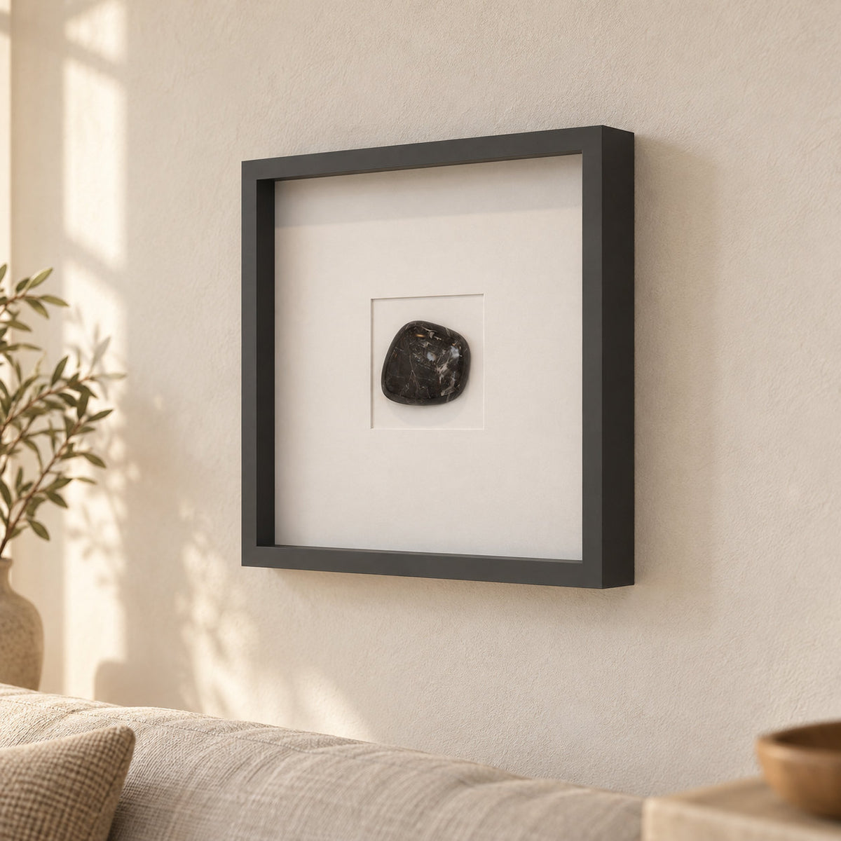 Right-side angled view of the ZenPebble dark stone wall decor in a charcoal frame on a warm cream wall