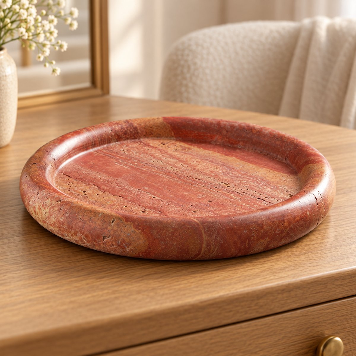 ScarletPebble red travertine round tray, low frontal view on a warm wood vanity