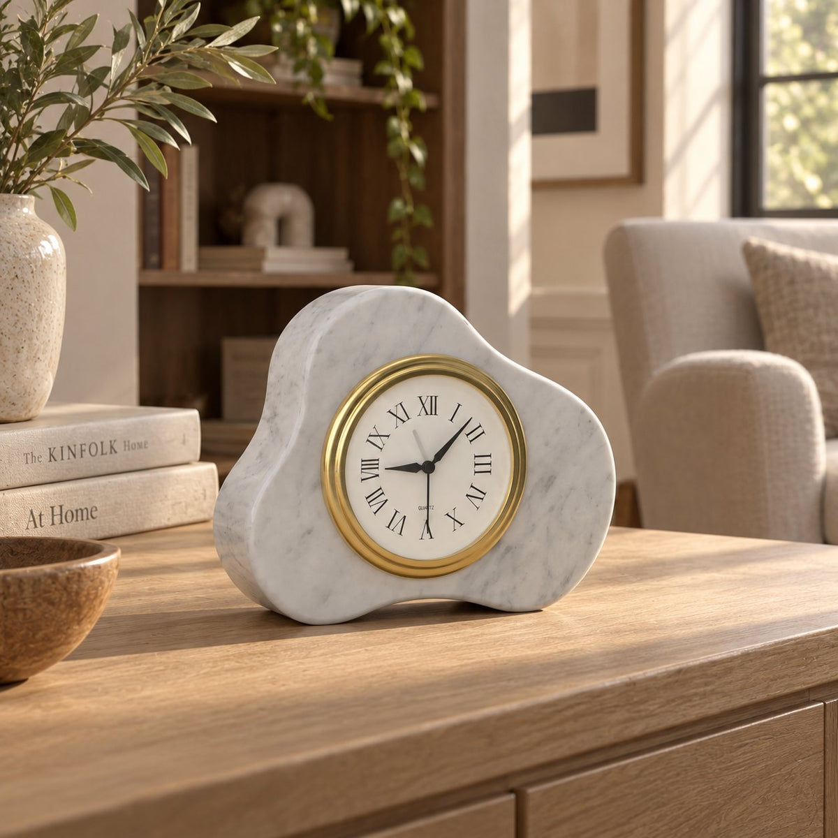 CloudDream Carrara marble tabletop clock, front-left oblique view on a sunlit oak console