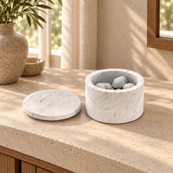 RoundHaven Carrara marble aroma diffuser with its matching flat lid and source styling stones, low front view in a warm sunlit interior