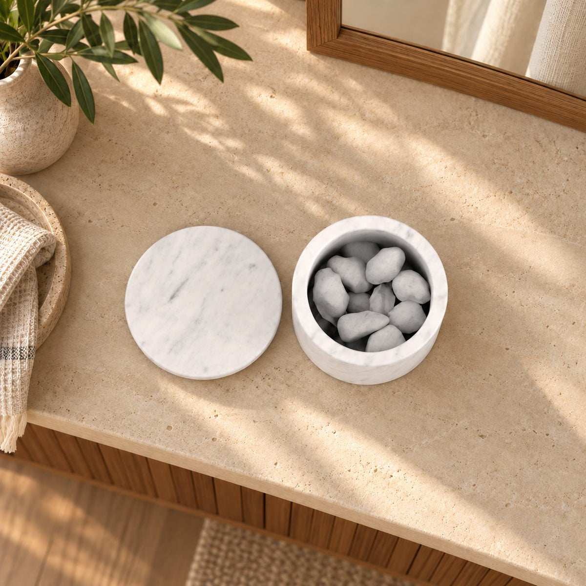 RoundHaven Carrara marble aroma diffuser with its matching flat lid and source styling stones, overhead view in a warm sunlit interior