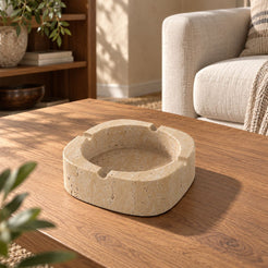 SquareSoft Classico travertine ashtray with four rim rests, left oblique view in a warm natural-light interior