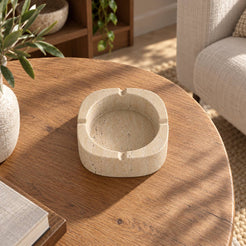 SquareSoft Classico travertine ashtray with four rim rests, overhead view in a warm natural-light interior