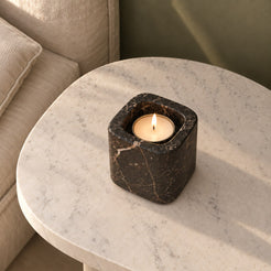 One Tall SquareSoft Spanish Emperador marble candle holder with a lit tealight, high oblique view on a warm stone table