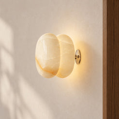 Donut white onyx wall lamp, single centred side three-quarter view with its wall mount, warm natural light