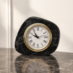 Black marble clock with gold Roman numeral dial on a dark stone tabletop