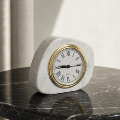 White marble tabletop clock with gold frame styled on a dark stone table