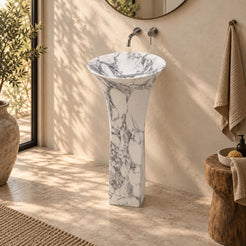 Paka Italian Arabescato Marble Pedestal Sink with a flared round basin and square stone pedestal in a warm ivory bathroom, front three-quarter view.