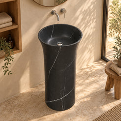 Pamala Portoro marble pedestal sink viewed from above in a warm bathroom with oak linen niche