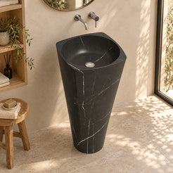Pamina Portoro black marble pedestal sink in a warm ivory bathroom with oak niche from a three quarter view