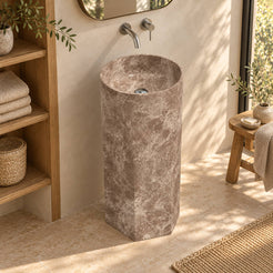Patali Dorata marble pedestal sink with faceted lower body in a warm bathroom with oak linen niche