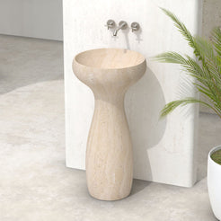 Pava beige travertine pedestal sink in a bathroom setting beside a white planter