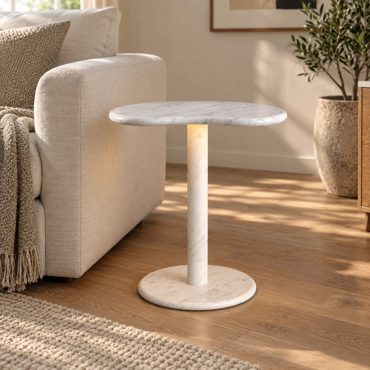 PeaPod Carrara marble smart-edition side table beside an ivory linen sofa, shown from a low front view