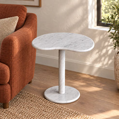 PeaPod white Carrara marble side table beside a rust reading chair, shown from a moderately elevated view