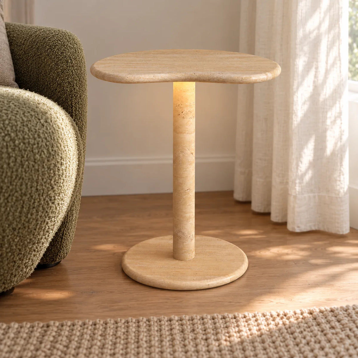 PeaPod Italian Classico travertine smart-edition side table beside a moss reading chair, shown from a low front view