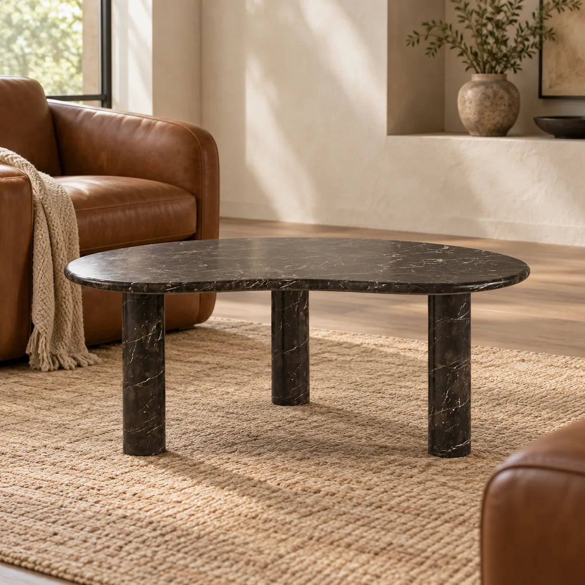 Low view of the PeaPod Dark Emperador marble coffee table beside a leather reading chair.