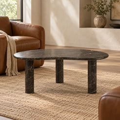 Low view of the PeaPod Dark Emperador marble coffee table beside a leather reading chair.