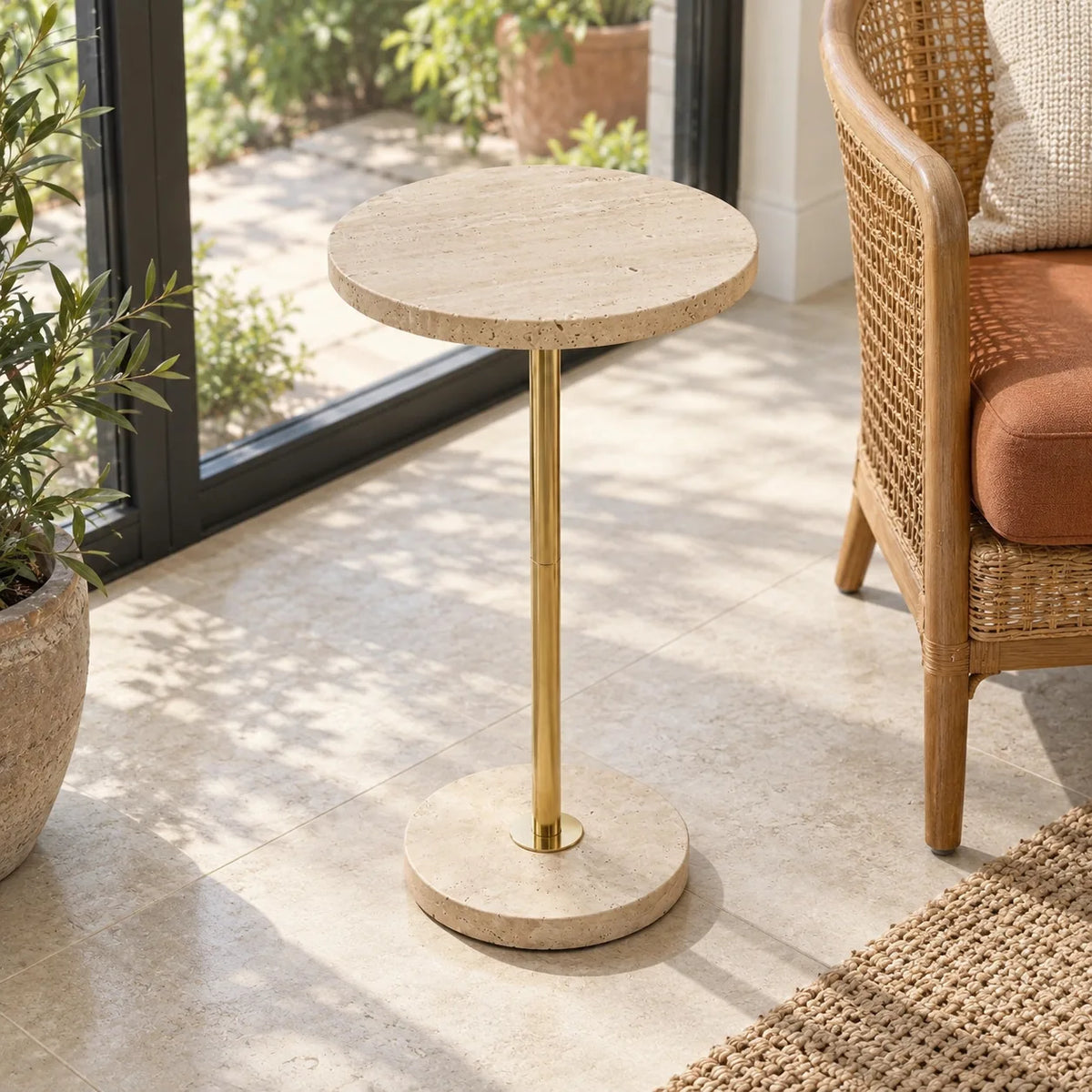 Pillar side table with a Classico travertine top and gold-finish metal stand viewed from a raised angle in a sunroom.