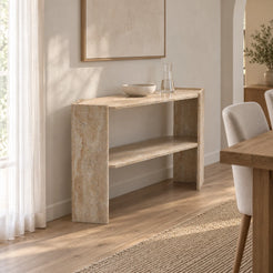 Left-front view of the Pomona beige travertine console table and lower shelf along a bright dining-room wall