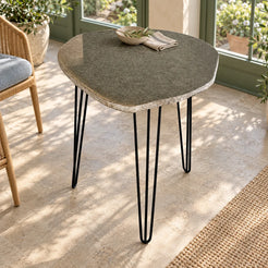 RiverStone natural river stone dining table with three black iron hairpin supports in a light-filled sunroom