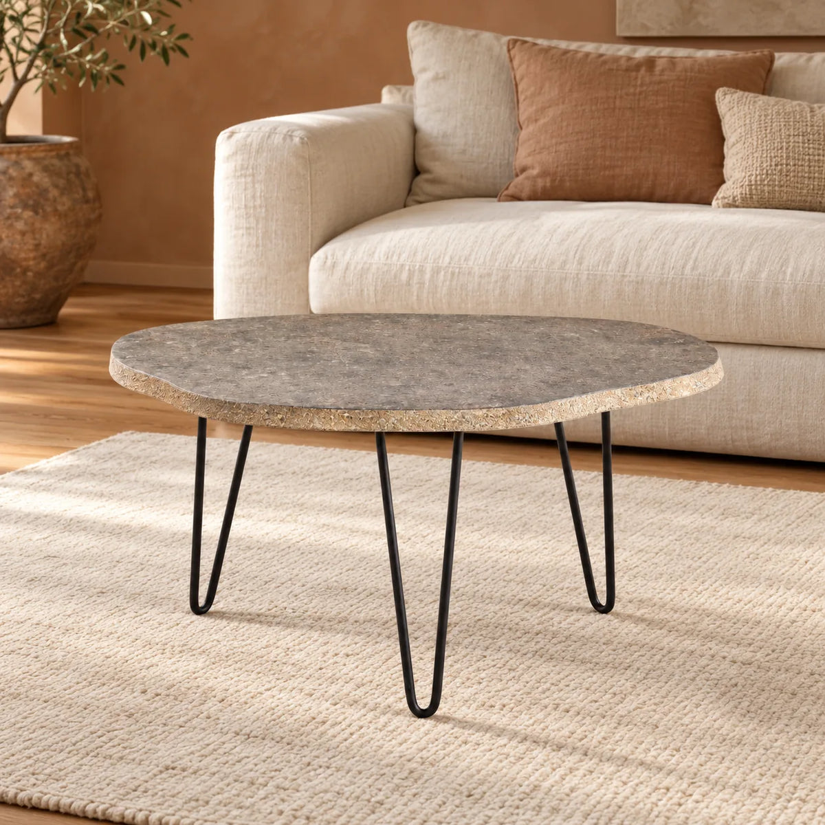 RiverStone Yellow River Stone coffee table with three black hairpin legs in a warm linen-sofa living room, viewed from the front