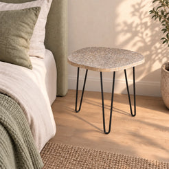 RiverStone Short natural river stone side table beside a sage linen bed, shown from an elevated right front view