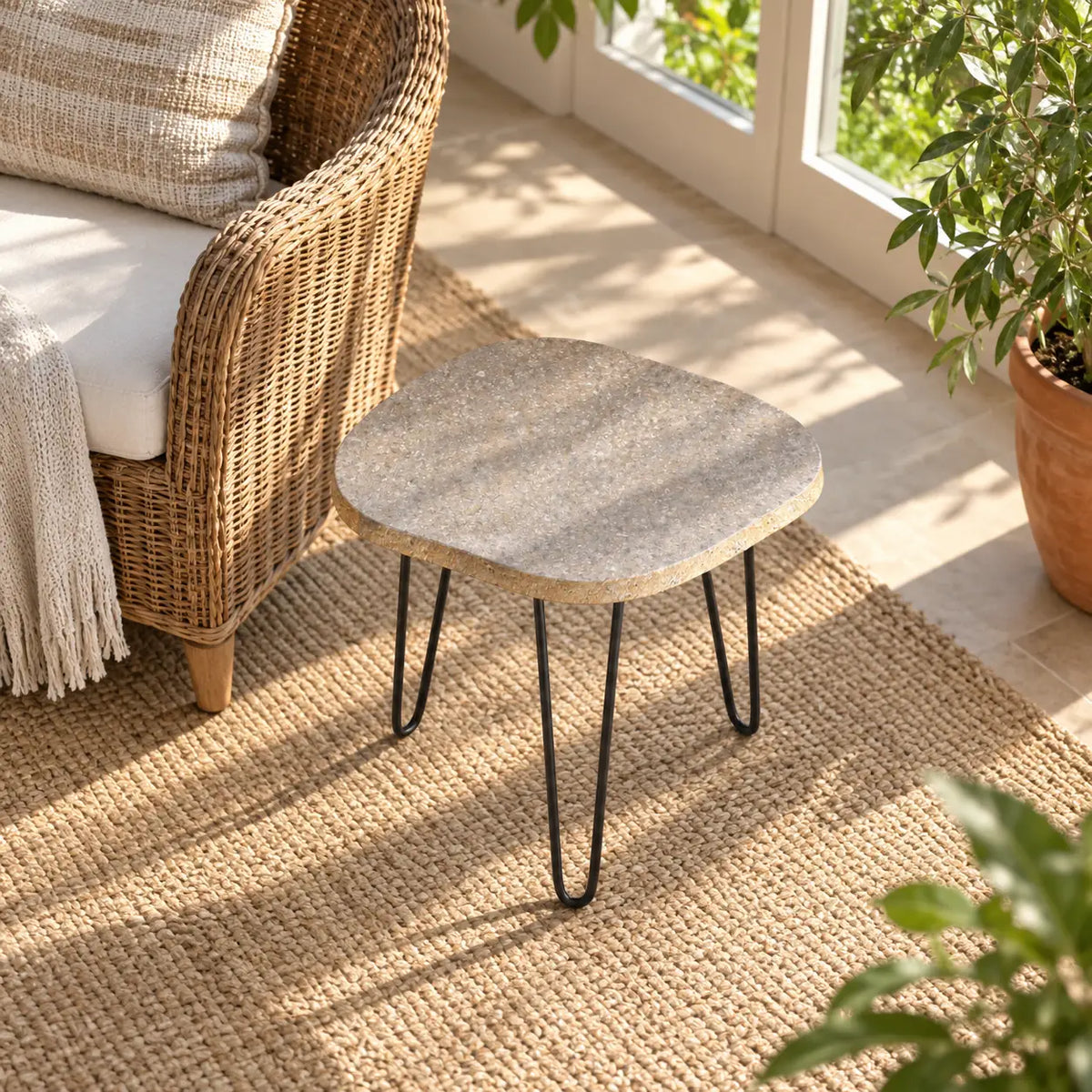 RiverStone Short natural river stone side table beside a wicker reading chair, shown from a high downward view