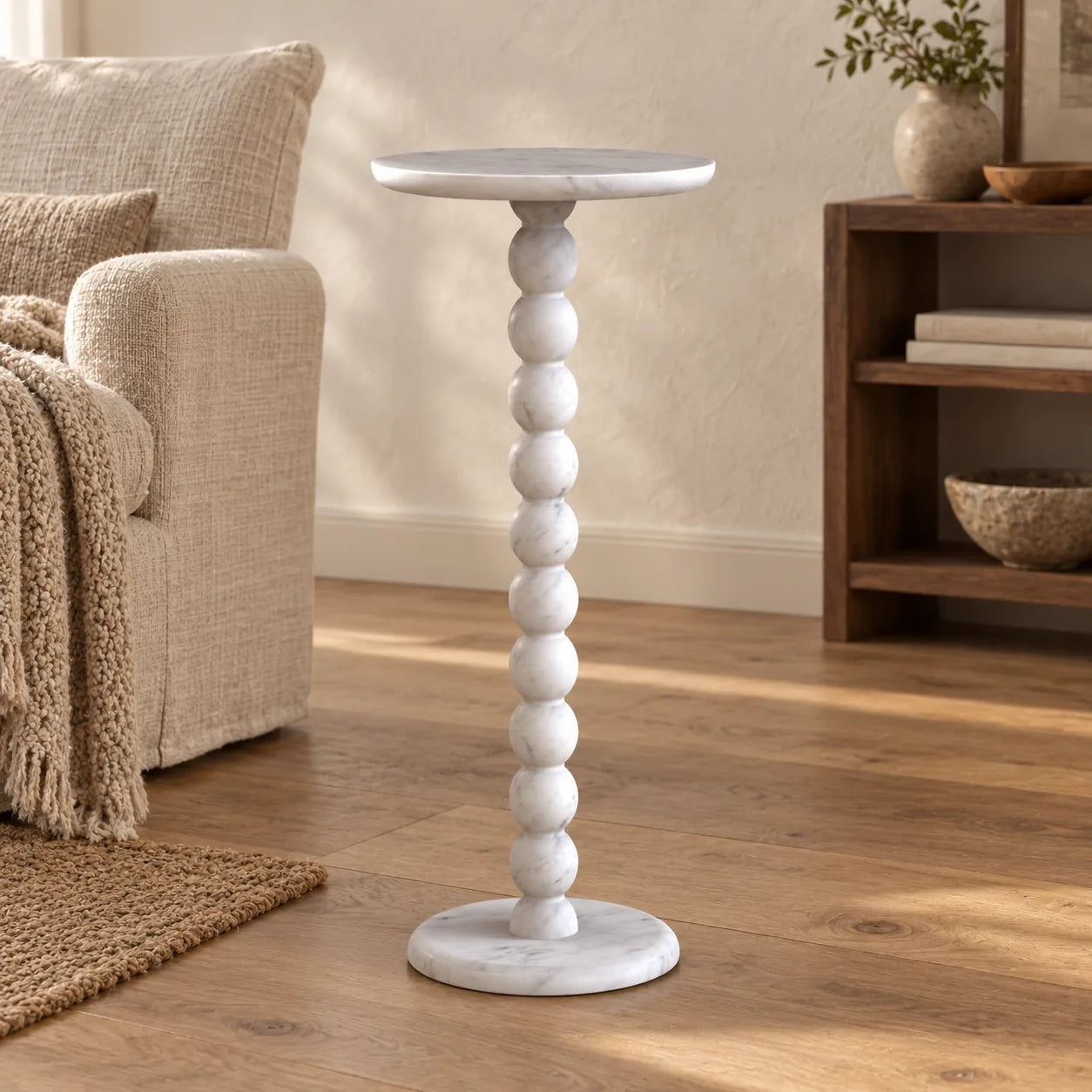 RoundBall Carrara marble cocktail table beside a linen lounge chair, shown from a low front view