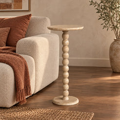 RoundBall Classico travertine cocktail table beside an oatmeal sofa, shown from a low front view
