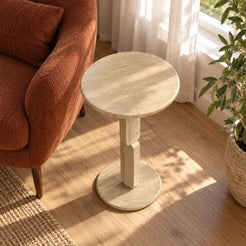 RoundGeo Italian Classico travertine side table beside a rust reading chair, shown from a high downward view