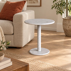 RoundHaven Carrara marble Standard side table beside a linen sofa, shown from a mid-height front-quarter view