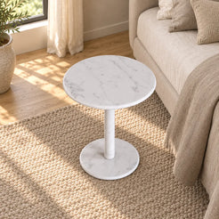 RoundHaven Carrara marble Standard side table in a linen bedroom, shown from an elevated front-quarter view