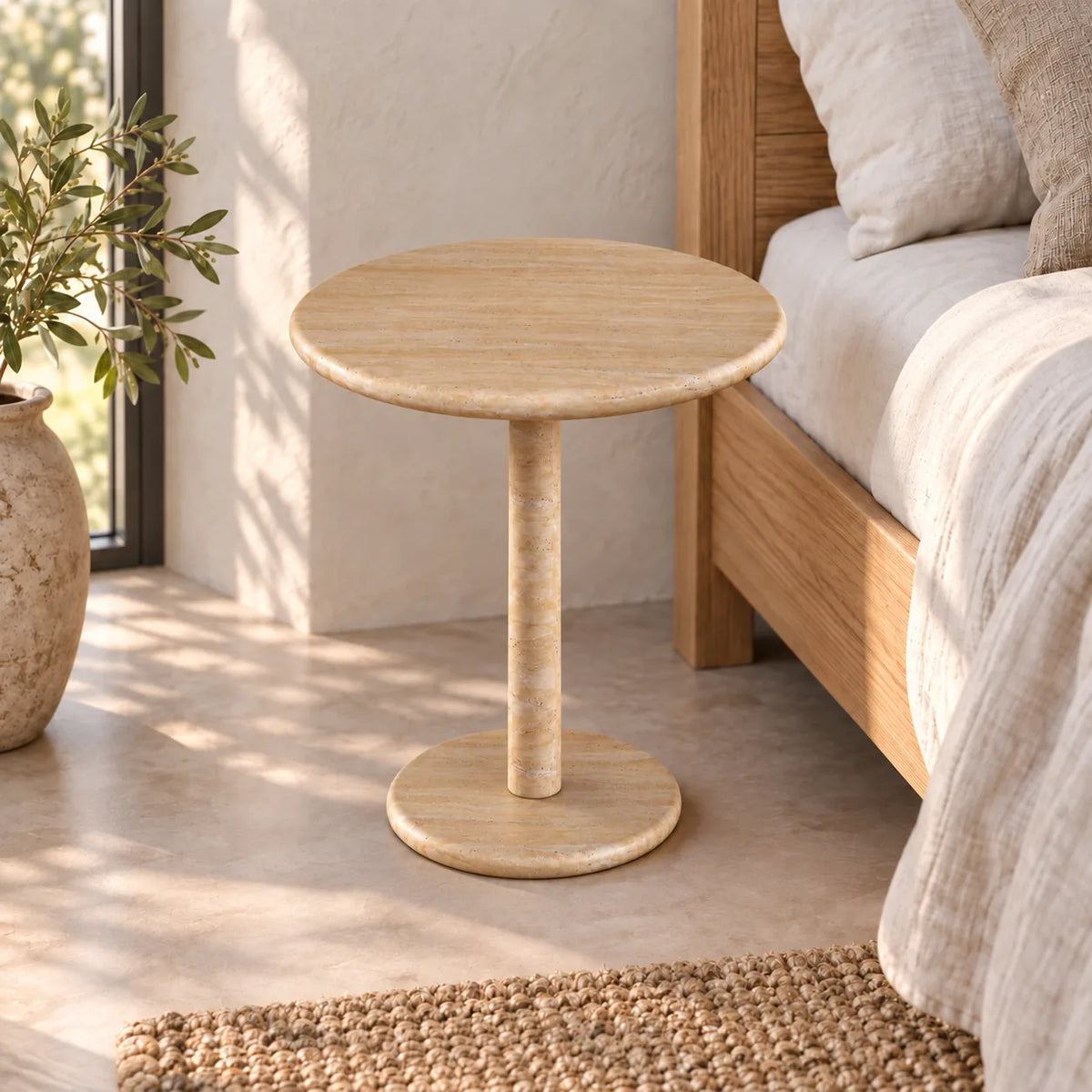 Moderate view of the RoundHaven travertine side table beside a timber bed.
