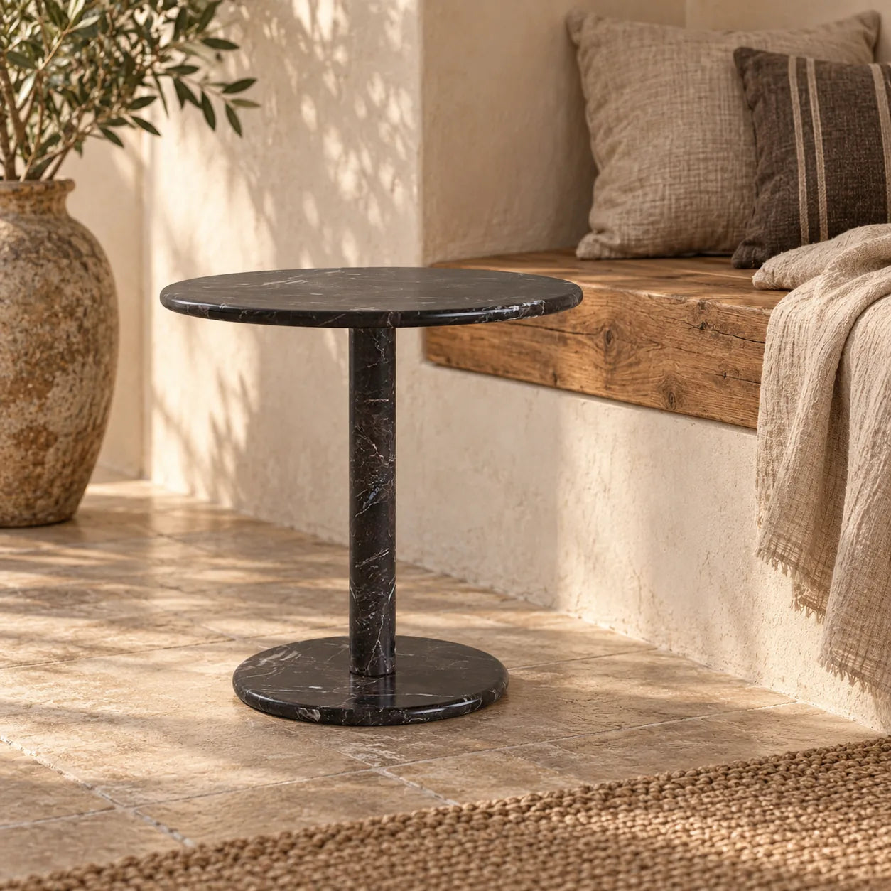RoundHaven Dark Emperador marble side table with a round top and circular base beside a timber bench.