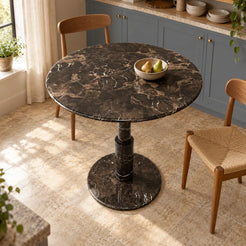 RoundTwin Elite Black dark marble dining table seen from a high oblique angle in a kitchen breakfast area, showing the round stone top, stepped cylindrical pedestal and circular floor base.